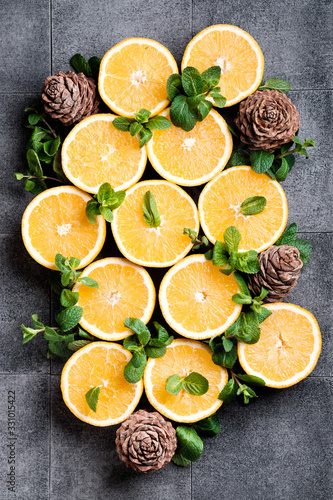 Fototapeta Naklejka Na Ścianę i Meble -  Oranges with mint and pine cones on a gray background