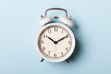 White vintage alarm clock on blue background. Time concept