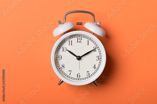 White vintage alarm clock on orange background. Time concept