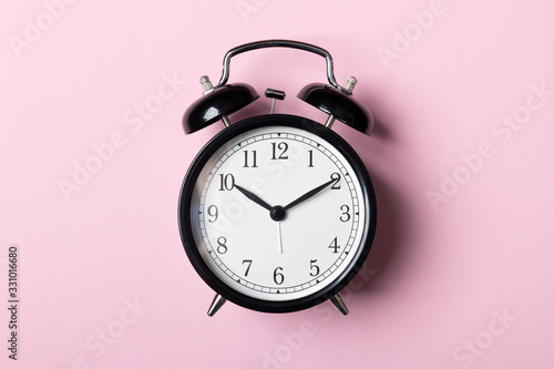Black vintage alarm clock on pink background. Time concept