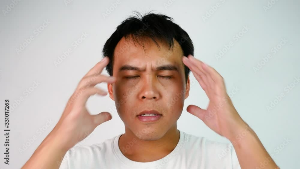 Close up portrait of Serious Asian man closing eyes and rubs his head expressing frustration and stressful over grey background. Emotion and expression concepts. Close up portrait of Serious Asian man closing eyes and rubs his head expressing frustration and stressful over grey background. Emotion and expression concepts.