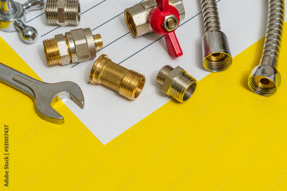 Plumbing spare parts and adjustable spanner closeup on the sheet for notes and preparation of a repair plan Plumbing spare parts and adjustable spanner closeup on the sheet for notes and preparation of a repair plan