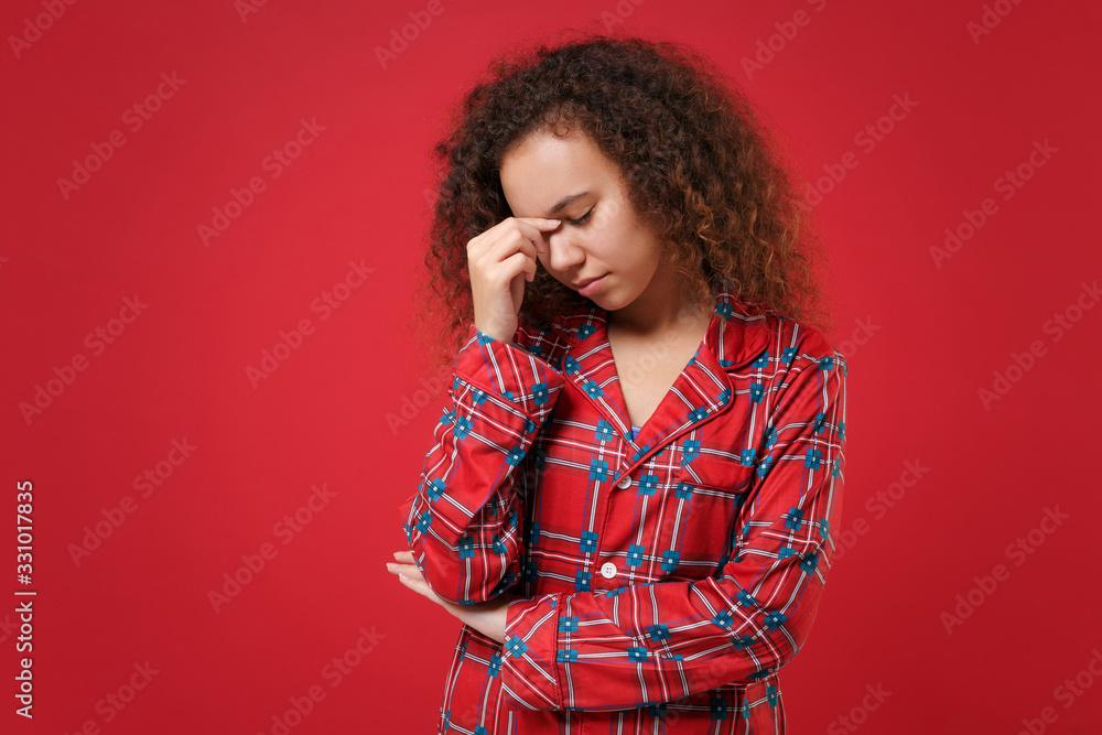 Tired young african american girl in pajamas homewear posing resting at home isolated on red background. Relax good mood lifestyle concept. Mock up copy space. Put hand on nose, keeping eyes closed. Tired young african american girl in pajamas homewear posing resting at home isolated on red background. Relax good mood lifestyle concept. Mock up copy space. Put hand on nose, keeping eyes closed.