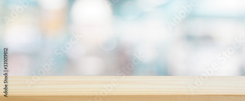 wood plank table top on blur and bokeh abstract in the department store with blue color tone using for design shopping background and banner montage display product layout