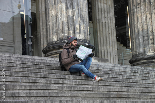 Tourist man sitting on stairs looking at map of the most famous places in the city