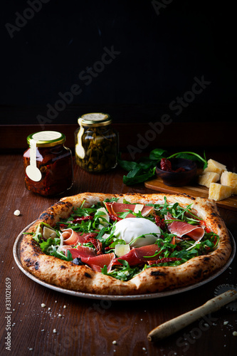 Pizza with prosciutto , arugula, burrata and parmesan cheese