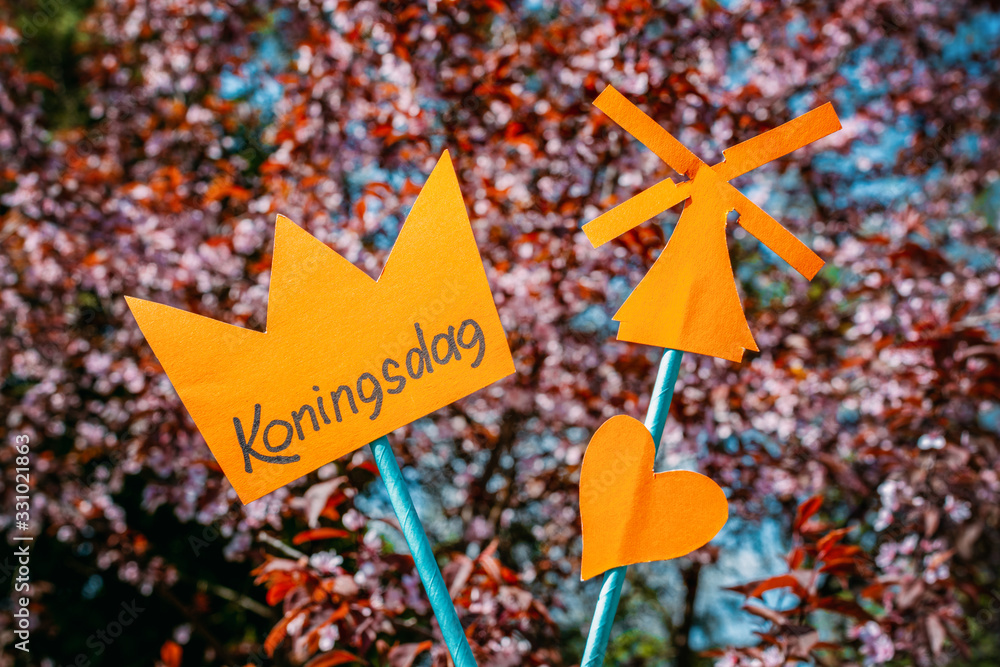 Paper cut crown with an inscription Koningsdag against the background of flowers
