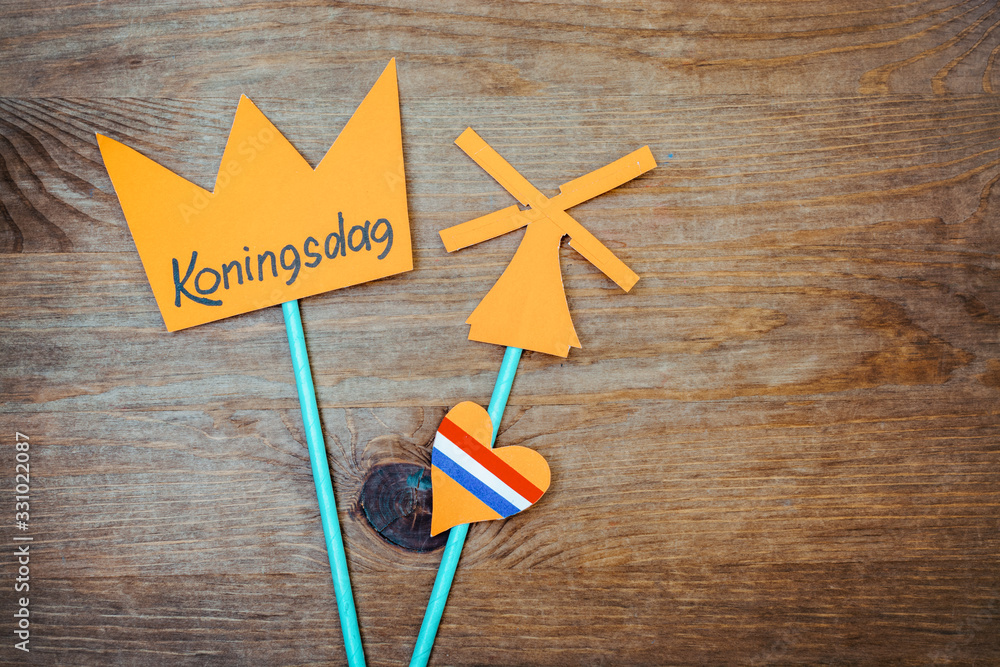 Mill, heart with the flag of the Netherlands and a crown with the inscription Koningsdag cut out of paper on wooden background