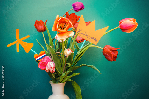 A paper-cut crown with the words Koningsdag stands in a vase with tulips. Koningsdag or King's Day is a national holiday in the Kingdom of the Netherlands.