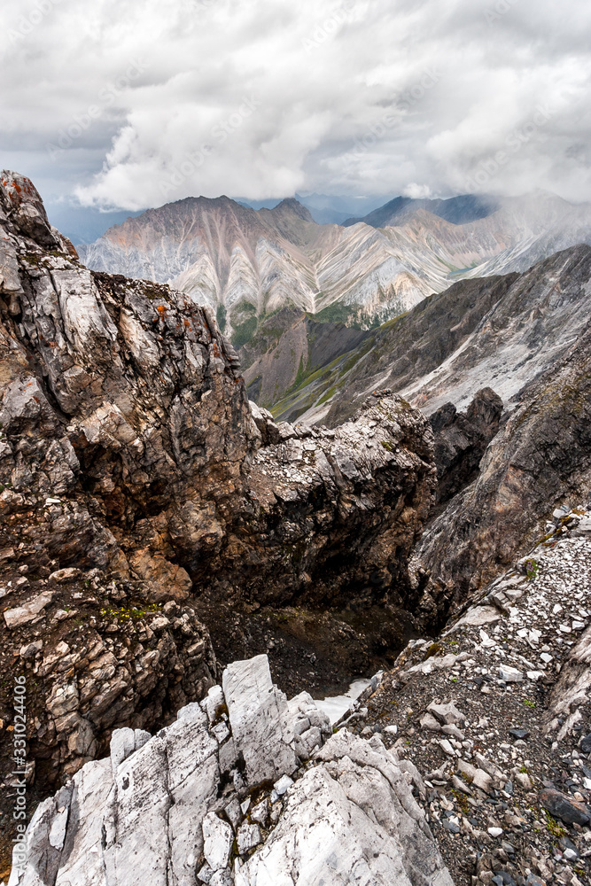 View from a high cliff to the mountains. Ancient cracked and unreliable stones. Cloudy weather. Vertical. View from a high cliff to the mountains. Ancient cracked and unreliable stones. Cloudy weather. Vertical.