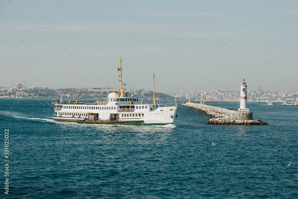 Beautiful view of the ferry sailing along the Bosphorus and the lighthouse against the backdrop of urban architecture
