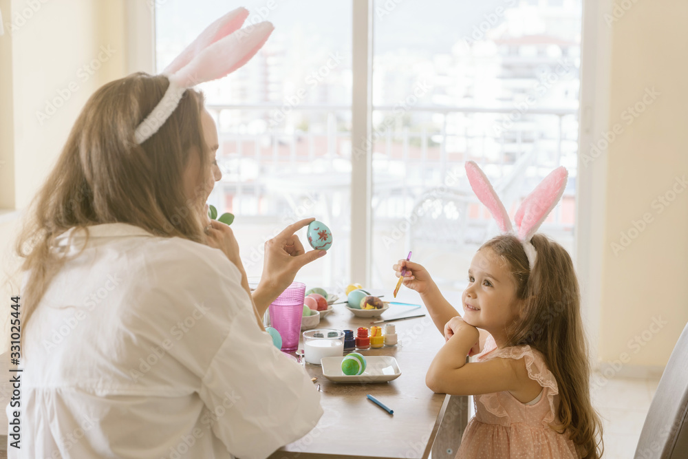 Little girl and woman with bunny ears laughing, smiling and having fun during decorate easter eggs. Little girl and woman with bunny ears laughing, smiling and having fun during decorate easter eggs.
