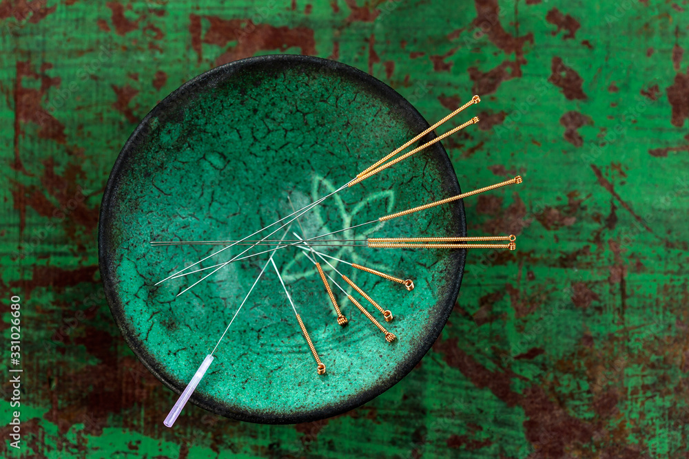 green ceramic Asian Bowl with needles for acupuncture on an old green paint wooden background - obrazy, fototapety, plakaty 
