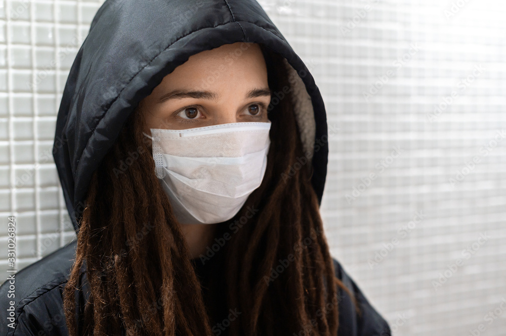 girl in a medical mask to a black hood on a white background