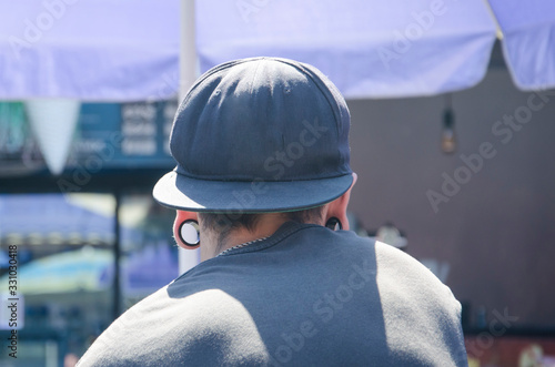 young man view from the back with tonnels in the ears and a cap