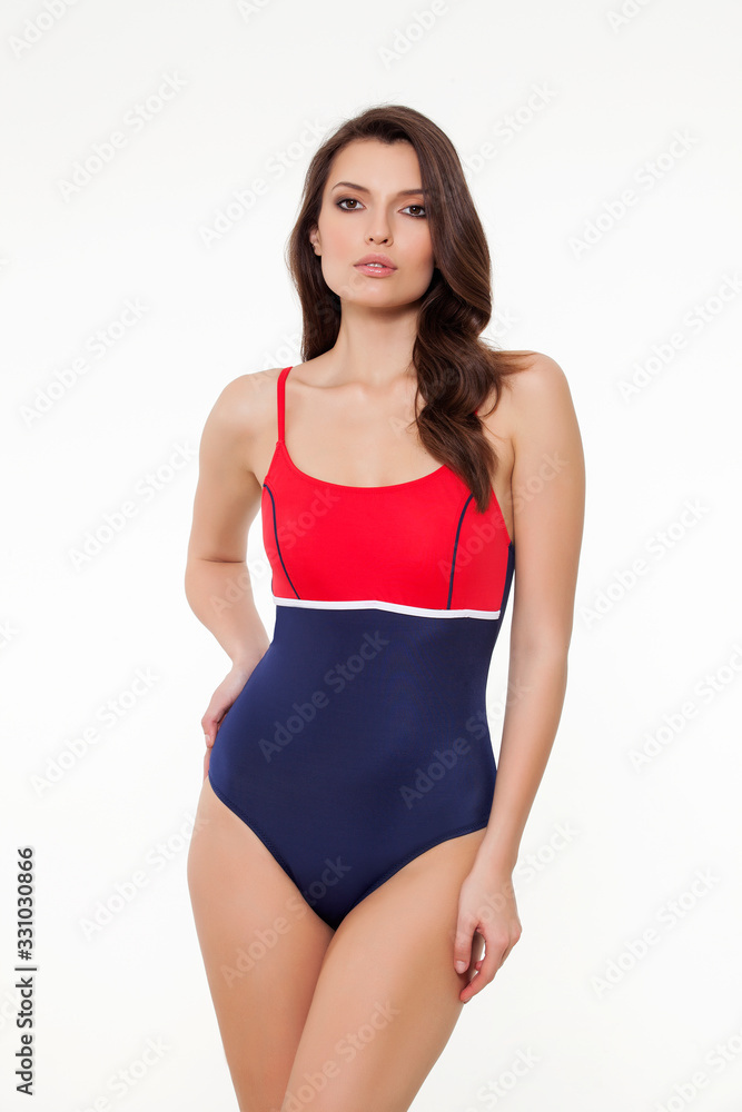 beautiful girl posing in stylish designed chic coral and navy blue swimsuit on white background. beautiful girl posing in stylish designed chic coral and navy blue swimsuit on white background.