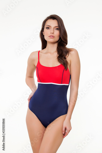 beautiful girl posing in stylish designed chic coral and navy blue swimsuit on white background.
