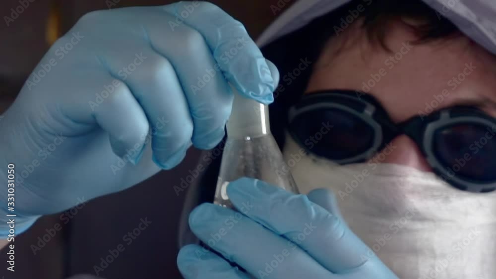 researcher in a protective uniform holds a dirty glass tube researcher in a protective uniform holds a dirty glass tube