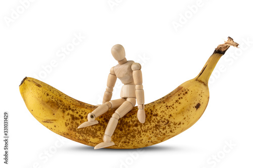 Wooden doll sitting on the ripe banana photo