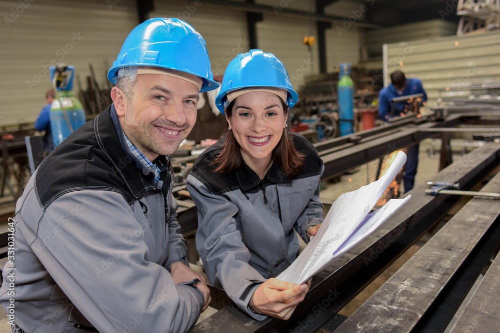 Two happy workers are smiling at the camera in a metal industry Two happy workers are smiling at the camera in a metal industry