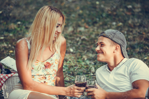 Beautiful smiling couple on the park making a picnic and drinking wine