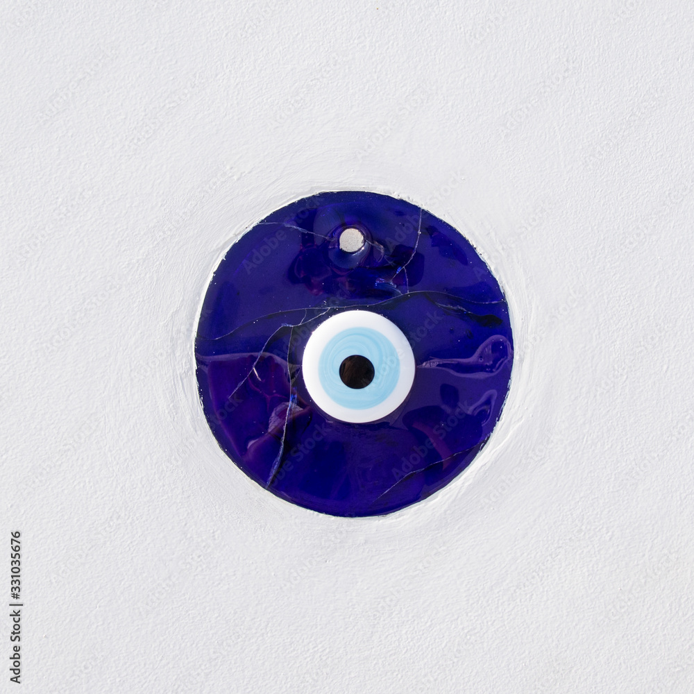 Occhio di Allah, amuleto greco e turco contro il malocchio. Vetro blu  incastonato su muro bianco Stock Photo