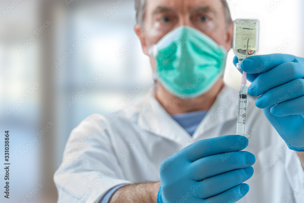 The doctor fills a syringe with vaccine on blurred background. The doctor fills a syringe with vaccine on blurred background.