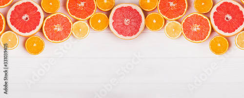 Different kinds of slice citrus fruits on white wooden background