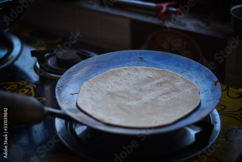 woman cooking a Indian chapati in a pan  