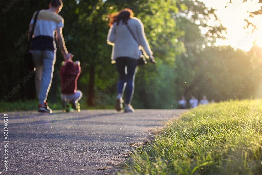 Obraz premium Happy family - mom, dad and kid - on a walk in the park in summer.