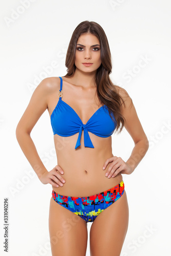 beautiful girl posing in stylish designed blue bikini on white background.