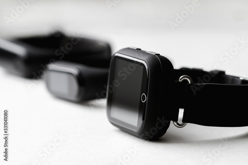 A row of fitness trackers and smart watch on white background. Closeup, selective focus