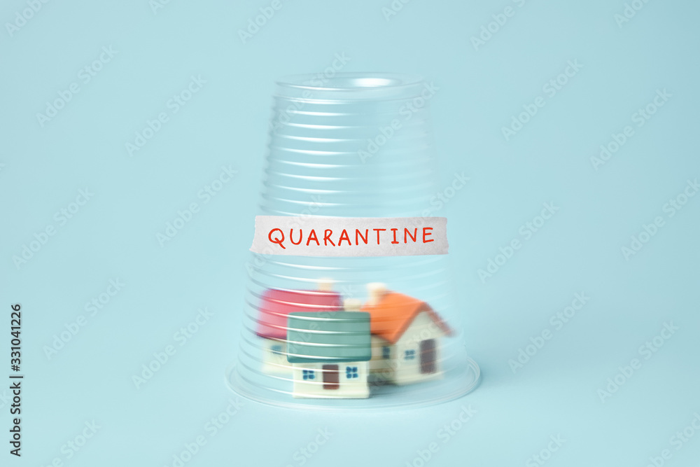 Coronavirus quarantine concept. Small houses covered with transparent plastic cup and inscription Quarantine