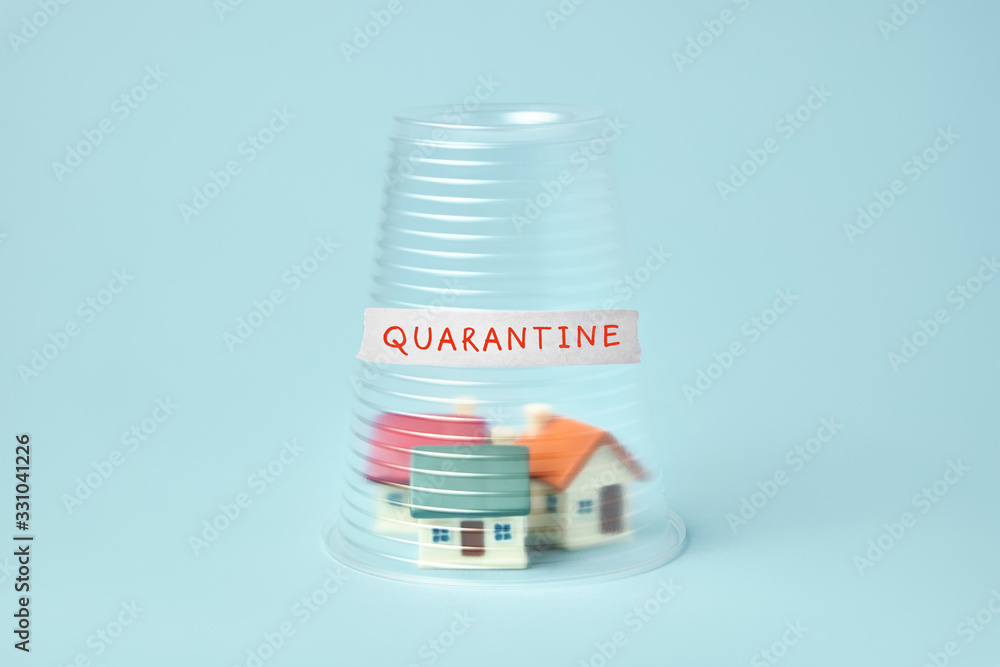 Coronavirus quarantine concept. Small houses covered with transparent plastic cup and inscription Quarantine Coronavirus quarantine concept. Small houses covered with transparent plastic cup and inscription Quarantine