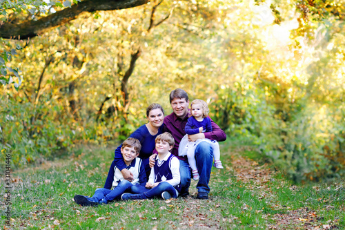 Portrait of young parents with three children. Mother, father, two kids brothers boys and little cute toddler sister girl having fun together in autumn forest. Happy family of five © Irina Schmidt