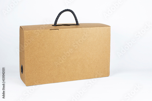 Cardboard box with black handle on light background. The box is intended for packaging of shoes, clothes