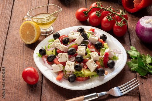 Greek salad with fresh cucumber   tomatoes  sweet pepper  lettuce  red onion  feta cheese and olives with olive oil. Healthy diet