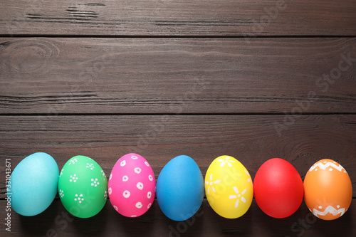 Colorful Easter eggs on wooden background, flat lay. Space for text