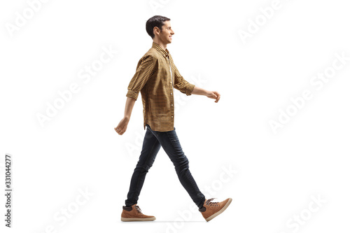 Casual young man in shirt and jeans walking with a smile photo