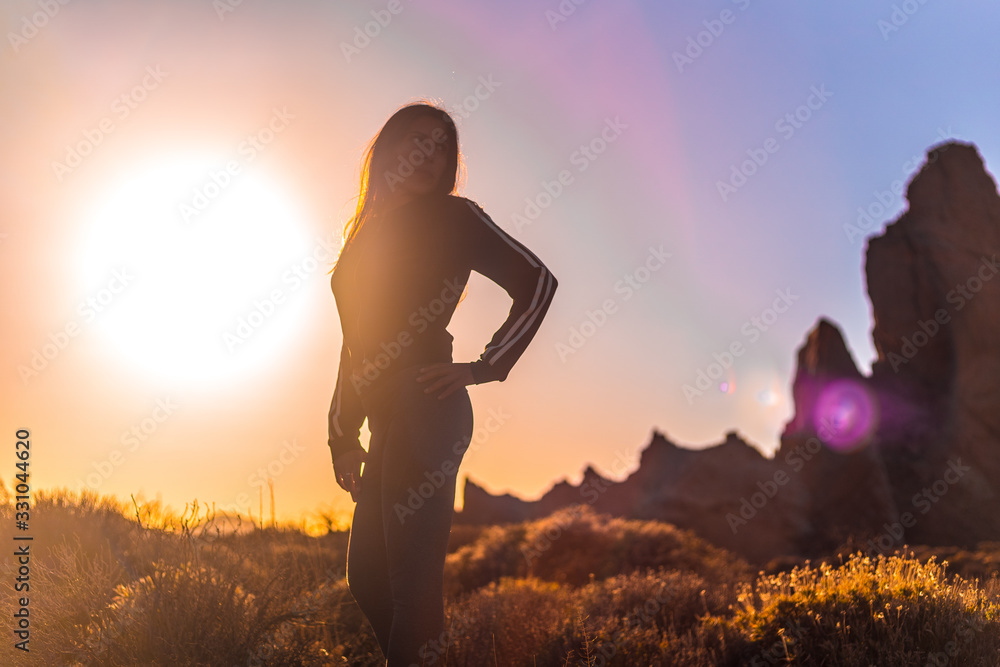 Lifestyle, silhouette of a young brunette in an orange sunset on the Teide volcano looking to the right. Tenerife