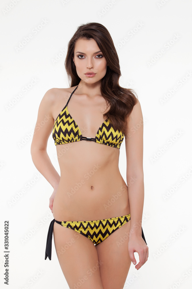 beautiful girl posing in stylish detailed black and yellow bikini on white background. beautiful girl posing in stylish detailed black and yellow bikini on white background.