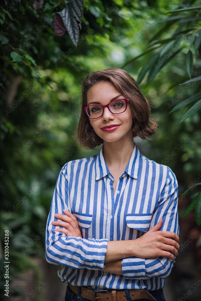 Young woman standing in botanical garden, looking at camera. Stock ...