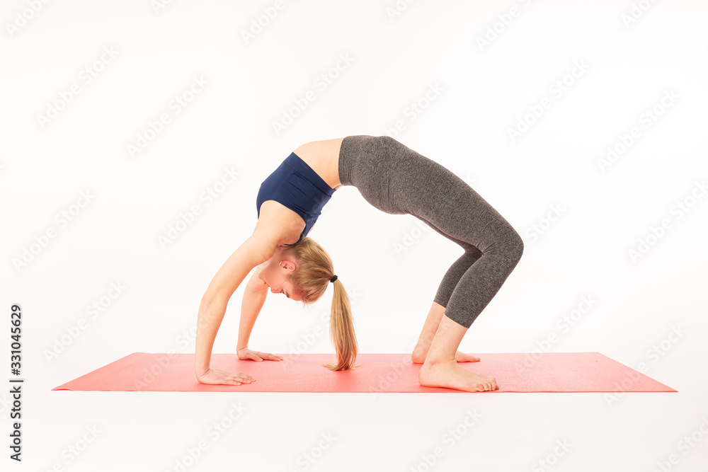 Young attractive yogi woman practicing yoga, stretching in Urdhva Dhanurasana exercise, Bridge pose, working out, wearing sportswear, blue sports bra, pants, indoor full length, isolated Young attractive yogi woman practicing yoga, stretching in Urdhva Dhanurasana exercise, Bridge pose, working out, wearing sportswear, blue sports bra, pants, indoor full length, isolated