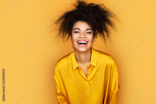 Overjoyed girl can't stopping laughing. Photo of african american girl on yellow background