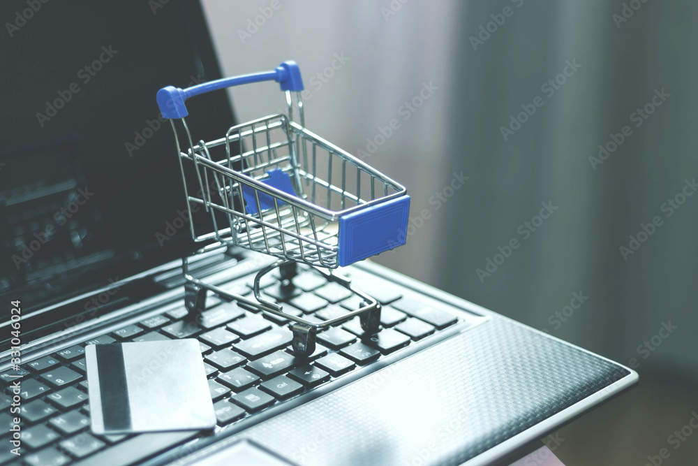 Shopping basket and credit card on laptop keyboard. Online shopping, home shopping