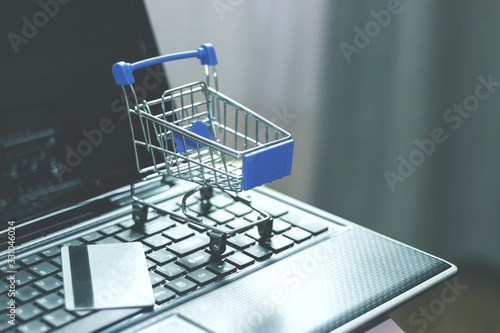 Shopping basket and credit card on laptop keyboard. Online shopping, home shopping