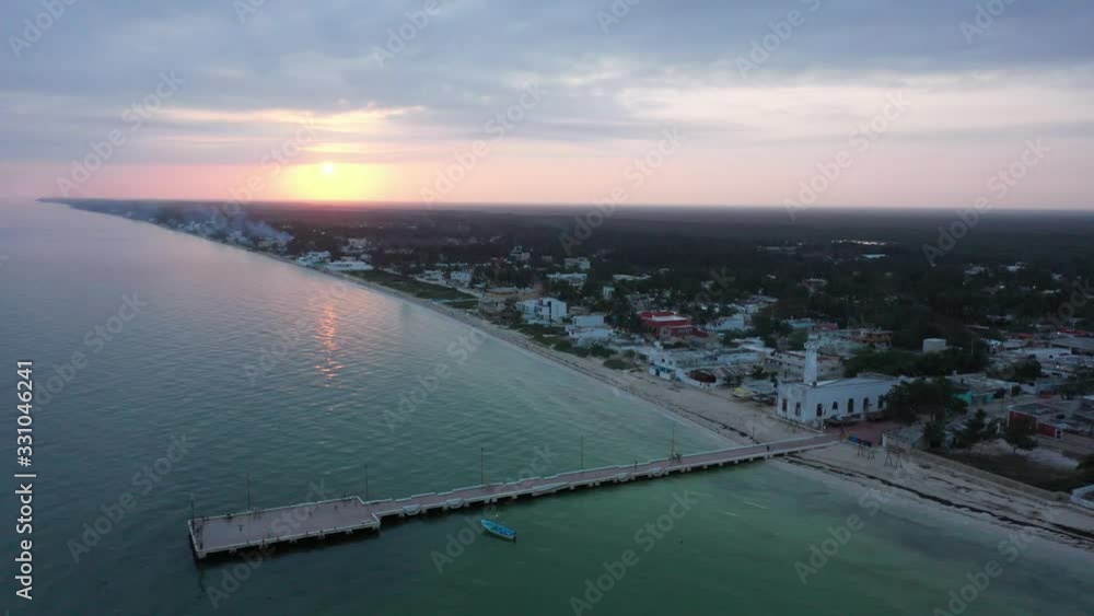 Aerial push in at sunrise showing the fishing pier, lighthouse and town of Telchac Puerto in Yucatan, Mexico.