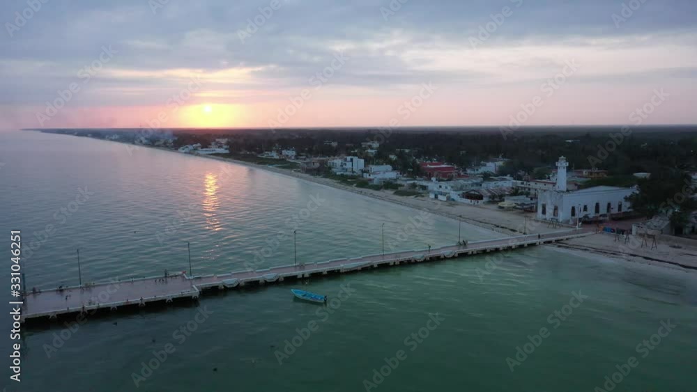 Aerial pull back at sunrise showing the fishing pier, lighthouse and town of Telchac Puerto in Yucatan, Mexico. Aerial pull back at sunrise showing the fishing pier, lighthouse and town of Telchac Puerto in Yucatan, Mexico.