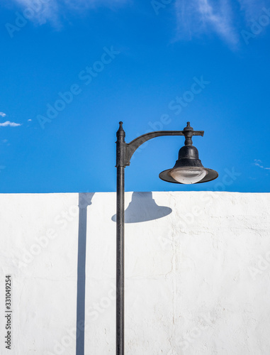 Lantern in sunlight and shadow on white wall