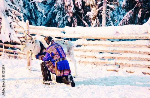 Man in Saami traditional garment at Reindeer in Finland photo